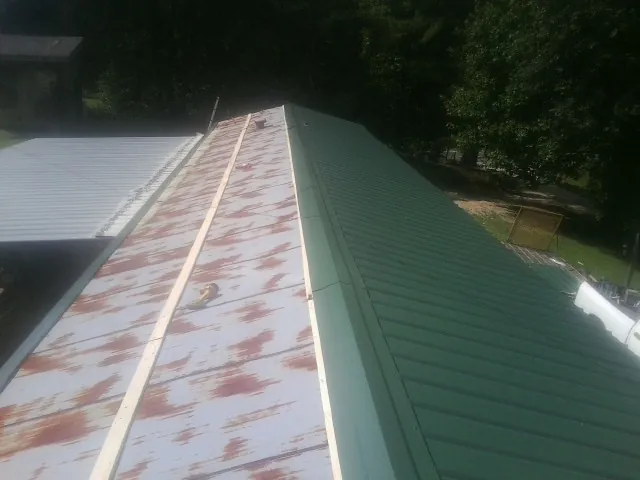Old rusted panels beside newly installed green metal roofing — Wind Damage Roof Repair by Roofing Brothers in Millis