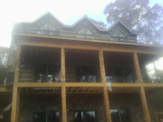 Dormers and porch framing on a large log home under construction in Millis