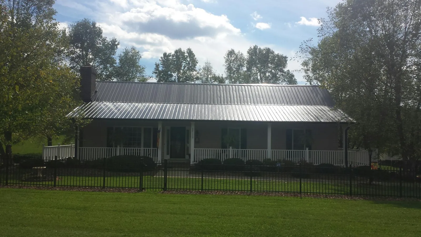 Gray metal roof on a brick ranch with a full width front porch — Gutter Guard Installation work by our crew in Millis